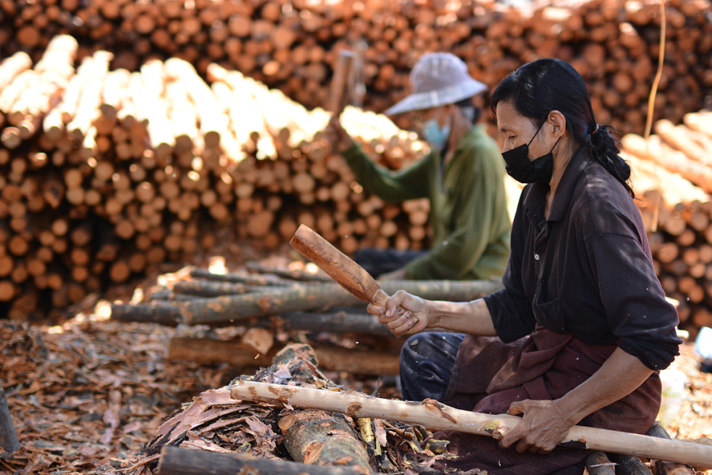 ภาพที่ 15 การทุบเปลือกของท่อนไม้หลาหรือไม้โกงกางก่อนนำไปเผา (ที่มา: https://www.anurakmag.com/made-in-thailand/02/17/2023/baan-yee-sarn)
